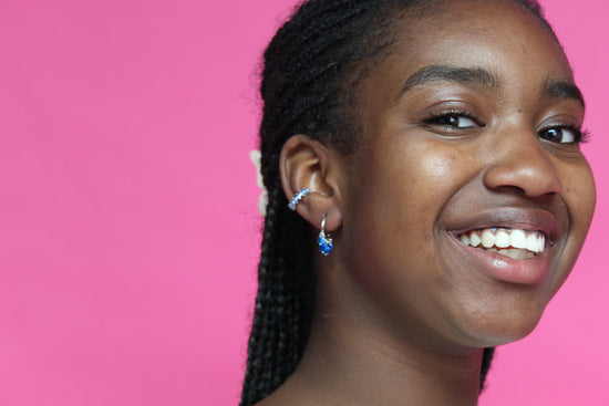 the girl is wearing gold huggie earring