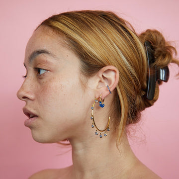the girl is wearing gold huggie earring