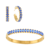 A Bijoux De Mimi gold jewellery set featuring a bangle bracelet, hoop earrings, all adorned with oval-cut blue gemstones.