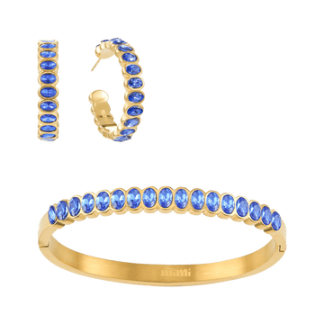 A Bijoux De Mimi gold jewellery set featuring a bangle bracelet, hoop earrings, all adorned with oval-cut blue gemstones.