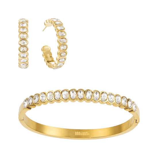 Bijoux De Mimi  Gold jewelry set featuring a huggie hoop earring and a matching bangle bracelet, both adorned with clear oval and round stones.